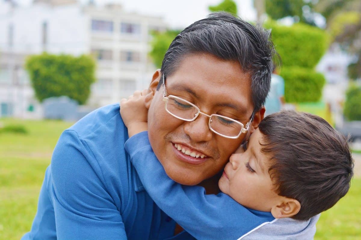 Tender portrait of native american man with his little son in the park.