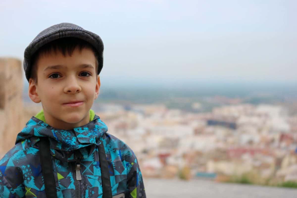 portrait of a young boy with the photo camera and the spanish old town on the background