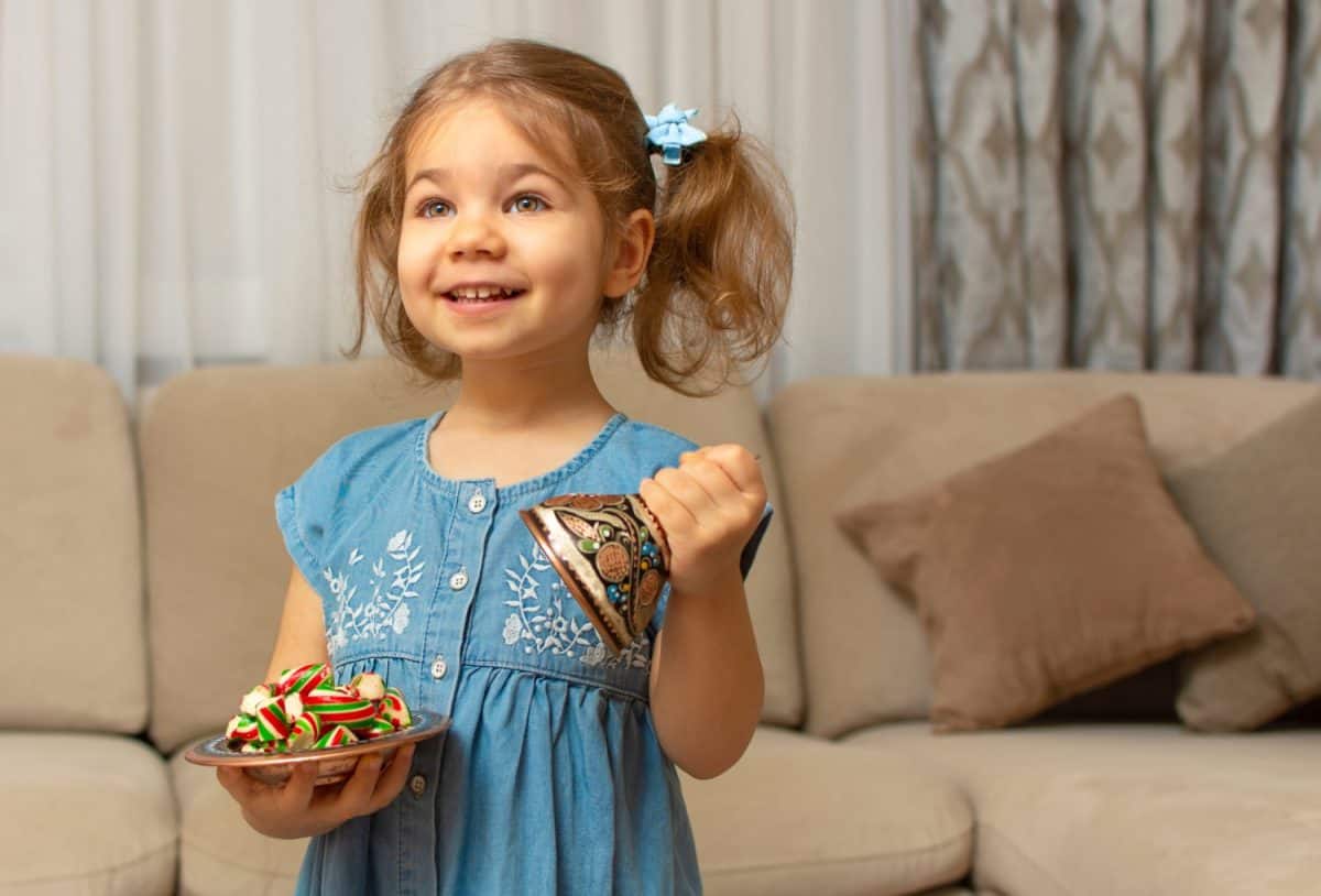 Child and traditional Ramadan candies. Colorful sweet and baby girl. Eid Mubarak. Kid hold plate full of sugar during Ramadan kareem (Turkish: Ramazan Bayrami).