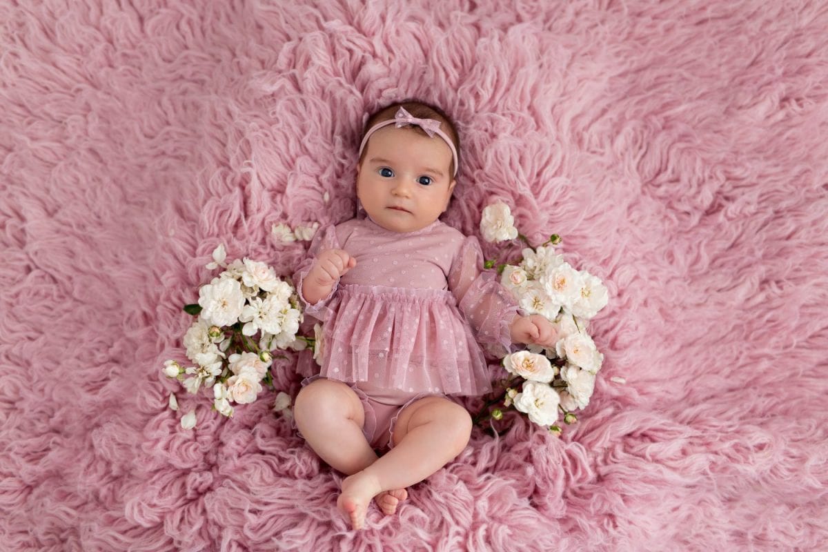 happy cute girl 3-5 months old lies on her back with flowers. Mothers Day. International Women's Day.