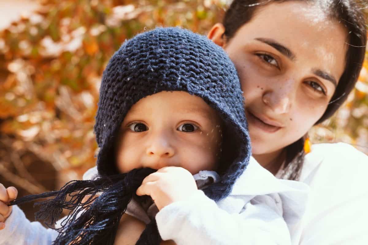 Mother holding her cute sweet son in autumn garden. Family time, mom and son in park