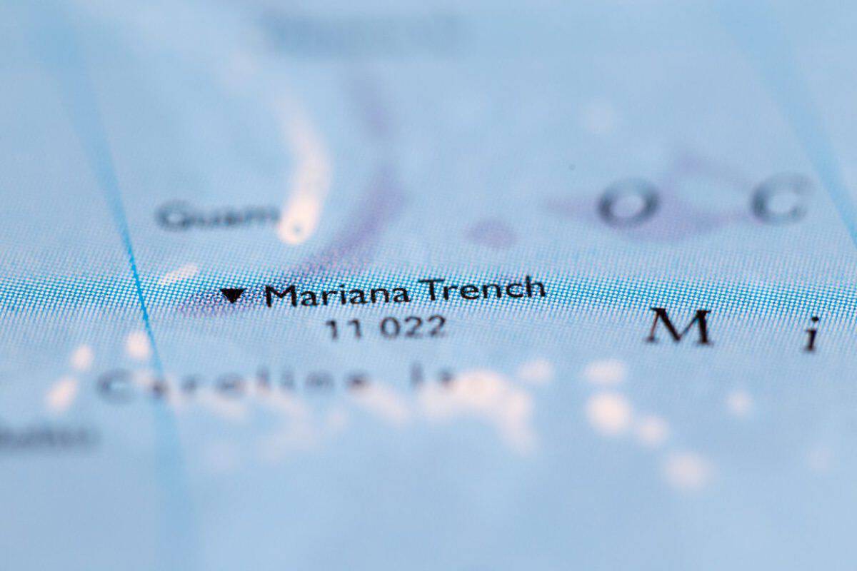 Shallow depth of field focus on geographical map location of Mariana Trench off coast of Philippines Pacific Ocean on atlas