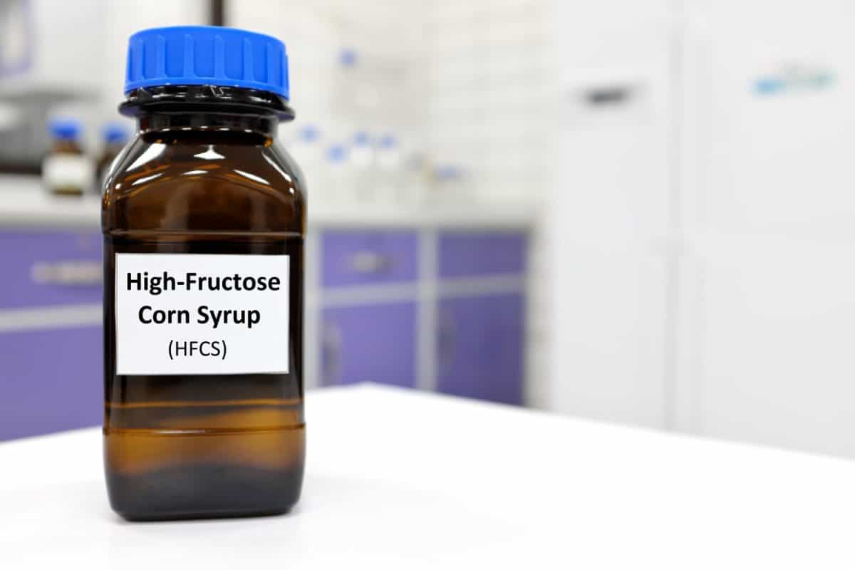 Selective focus of high-fructose corn syrup or hfcs food and beverage sweetener in dark brown glass bottle inside a laboratory.