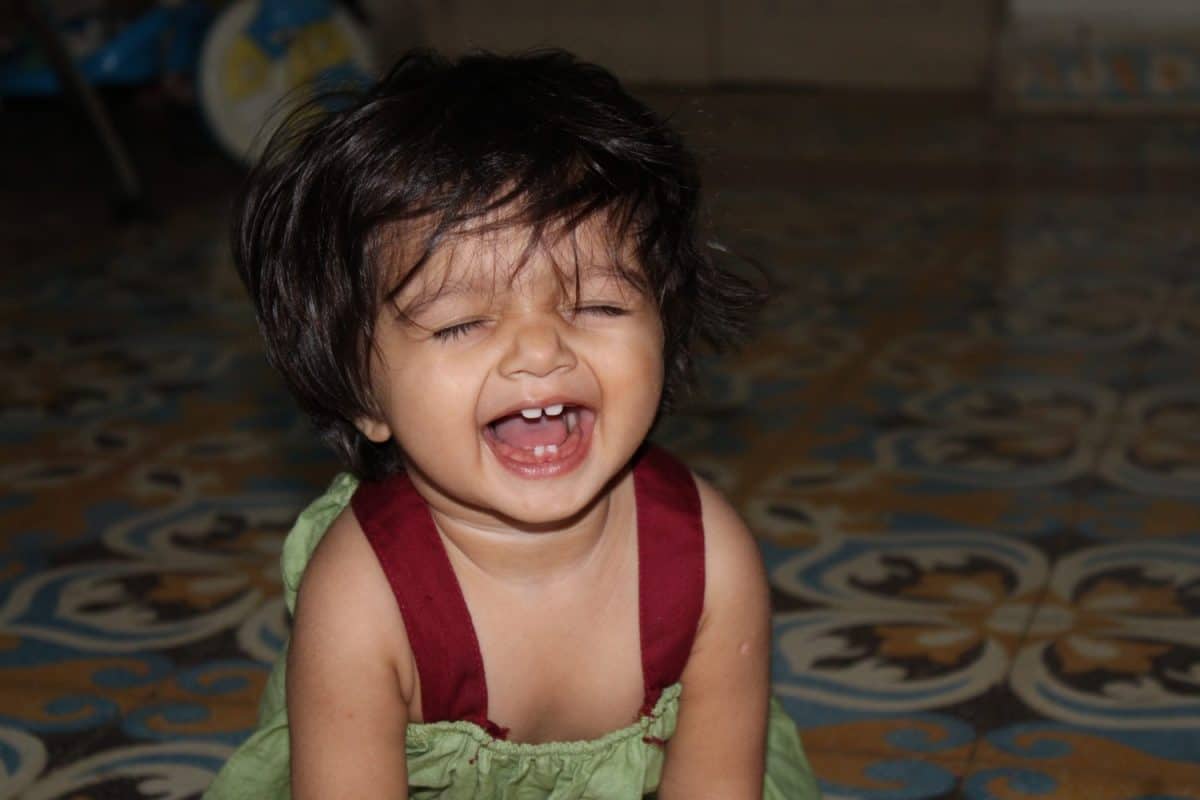 Indian baby girl playing in room smiling face with green frock and todler with new teeth