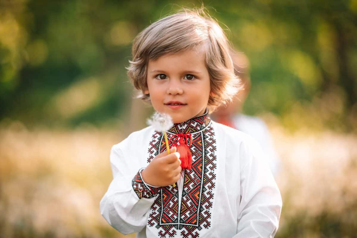 Portrait of little ukrainian boy with dandelion in spring garden. Child in traditional embroidery vyshyvanka shirt. Ukraine, freedom, national costume, happy childhood and future concept