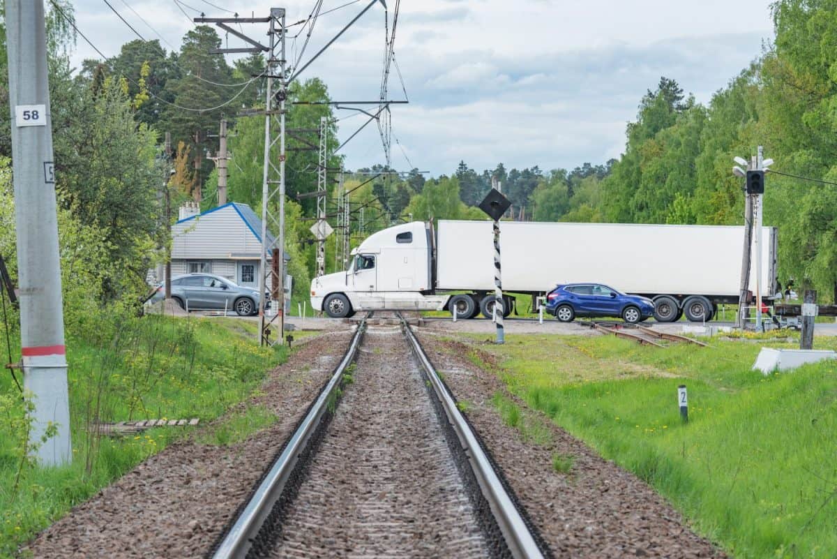 Cars cross the railroad track by the station.