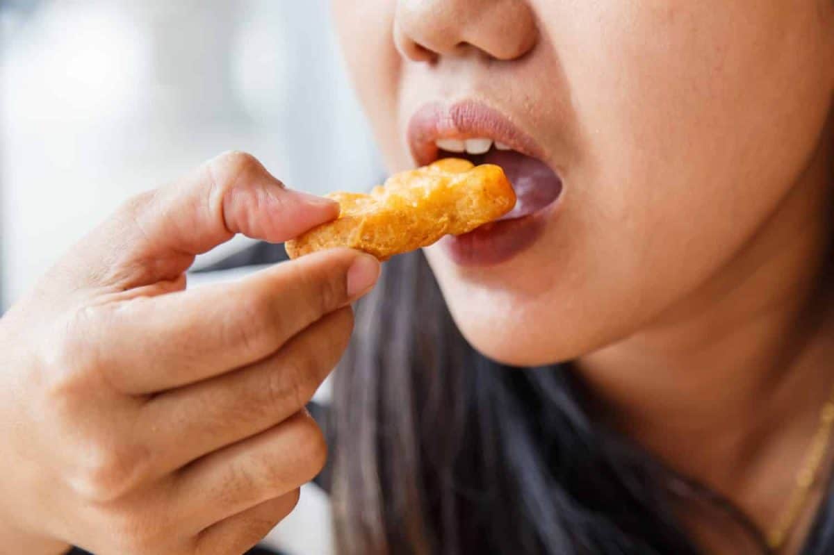 Hand holding Fried chicken nuggets and eating in the restaurant