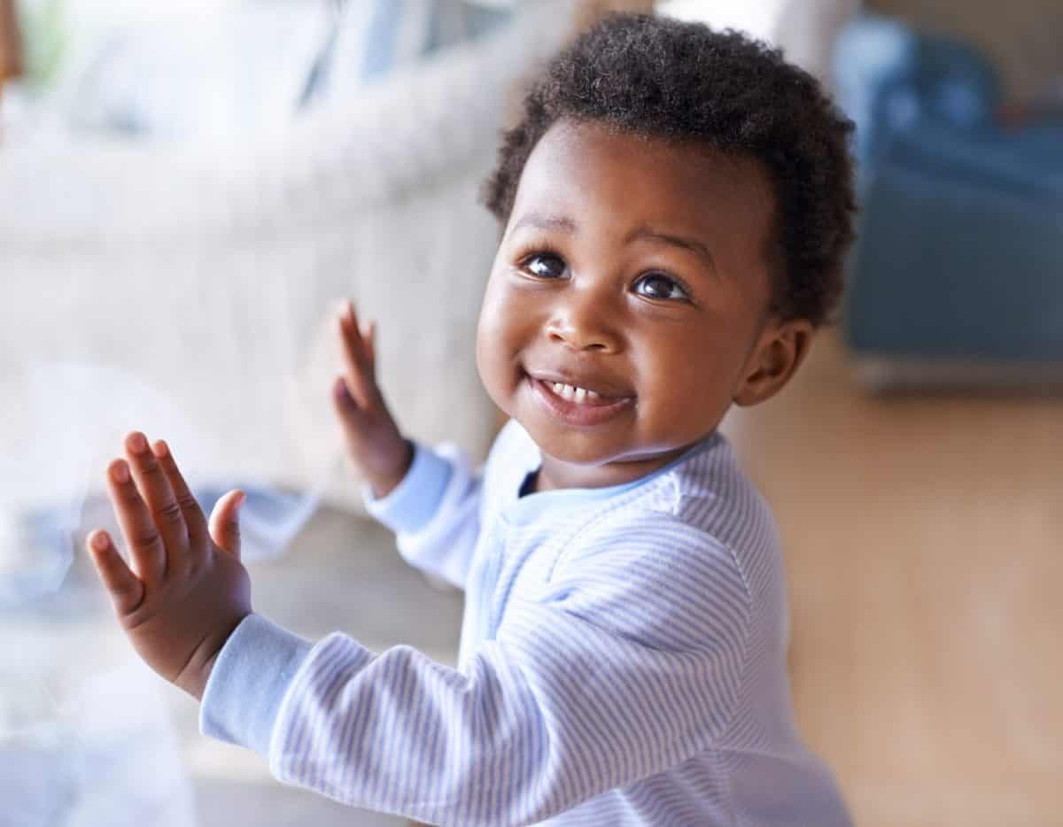 Happy black baby boy, childhood development and child with smile standing against window at family home. Happiness with African male toddler, growth and young cute kid at house with childcare