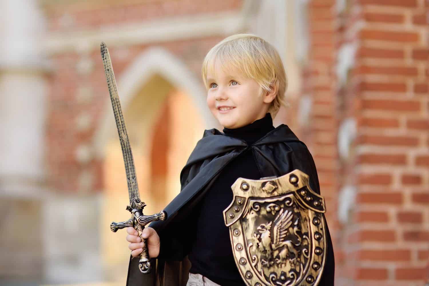 Portrait of a cute little boy dressed as a medieval knight with a sword and a shield. Medieval festival or costume party for kids