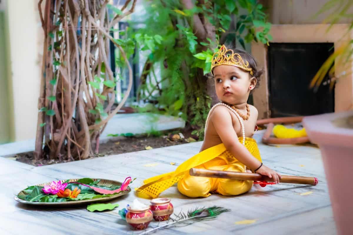 adorable infant dressed as hindu god krishna cute facial expression with flute at janmashtami