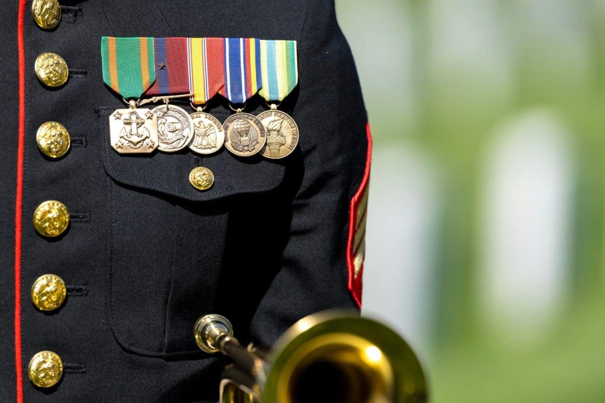 A poignant moment unfolds as a Marine plays taps, honoring a fallen veteran with a solemn salute, marking their internment at a national military cemetery.