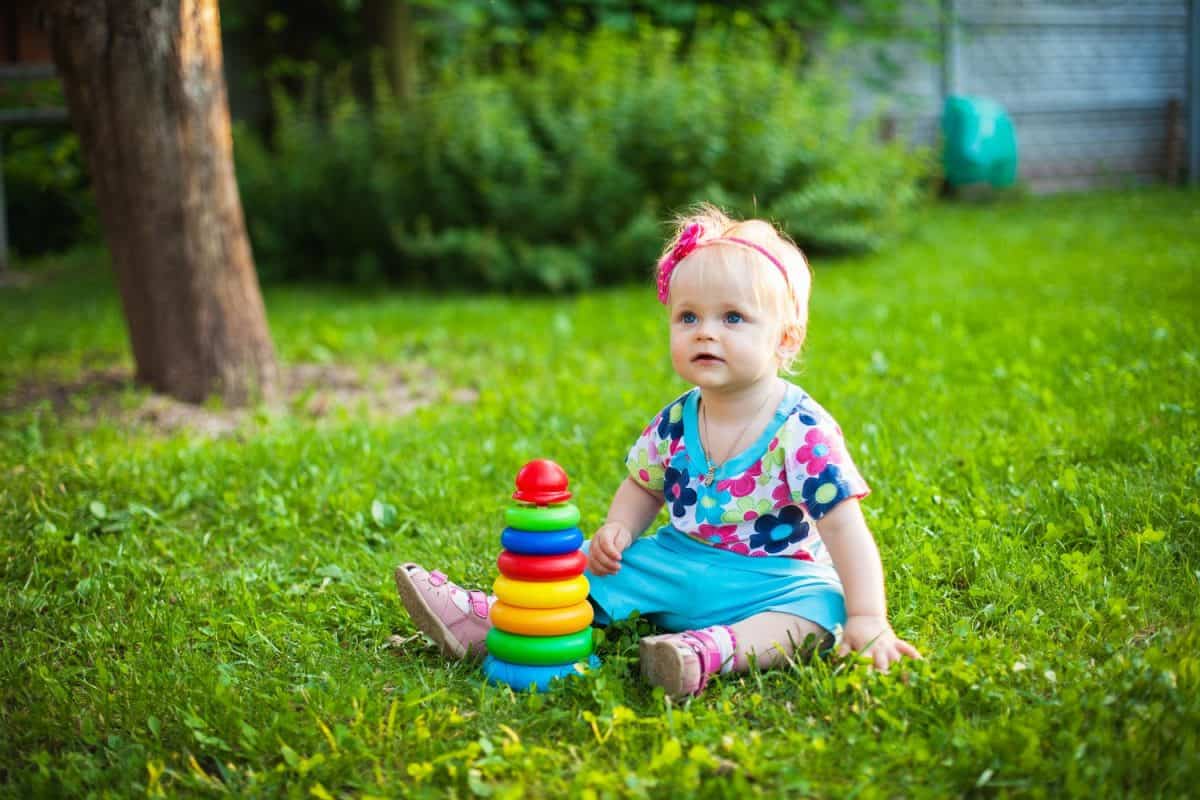 A cute little smiling girl playing with clover flowers in the meadow in a sunny summer day