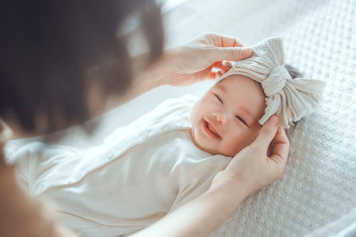 Happy excited baby newborn laughing at mom face, positive emotions, Mother wearing ribbon headband for her daughter, A happy family