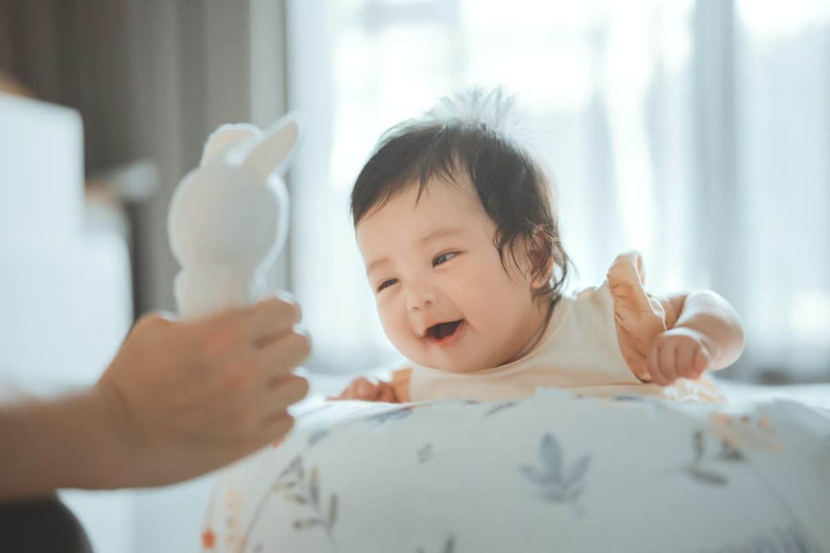 Cute little Asian 4 - 6 months old baby girl doing tummy time playing with her Mum, Newborn baby laying on stomach developing neck control