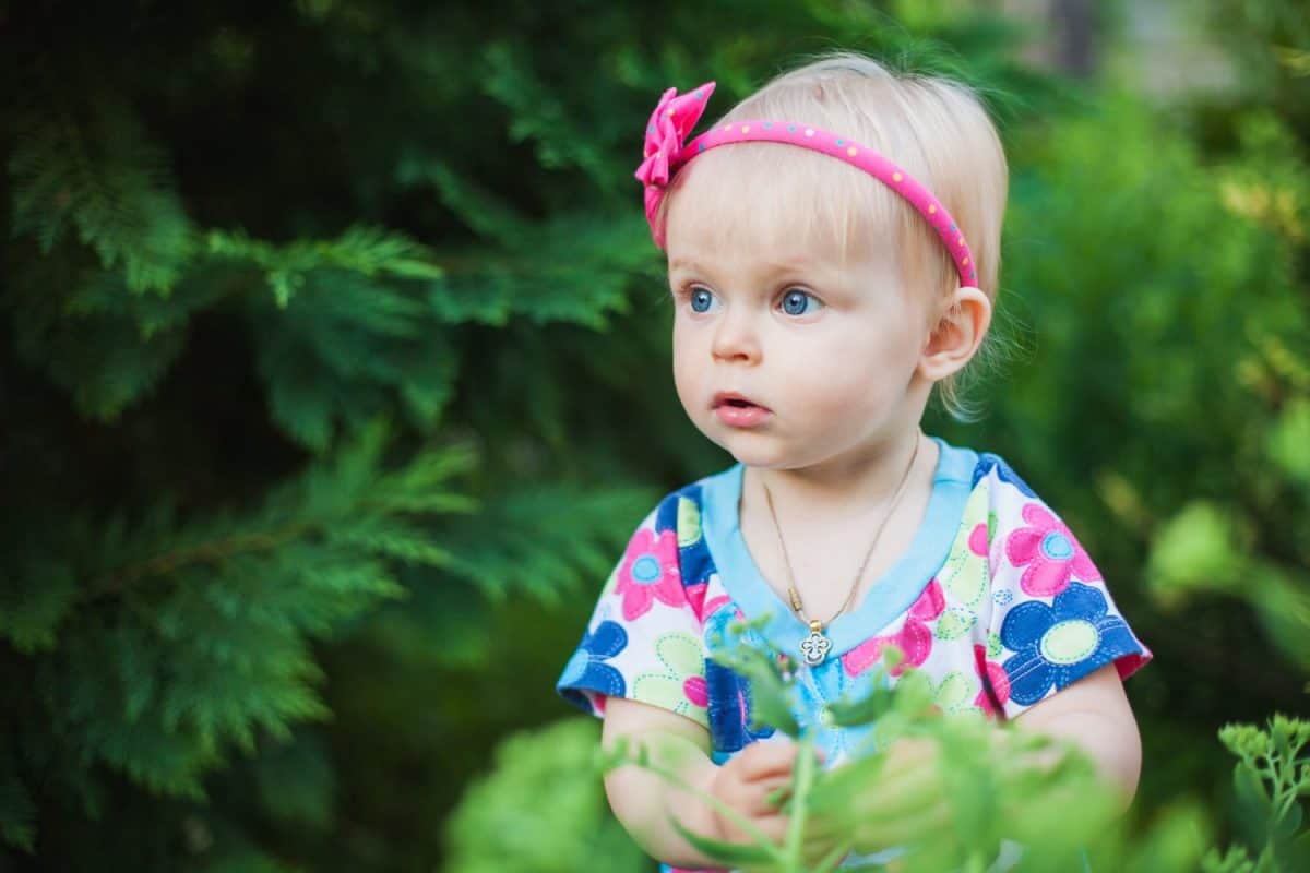 little baby girl playing with flowers in the park or garden