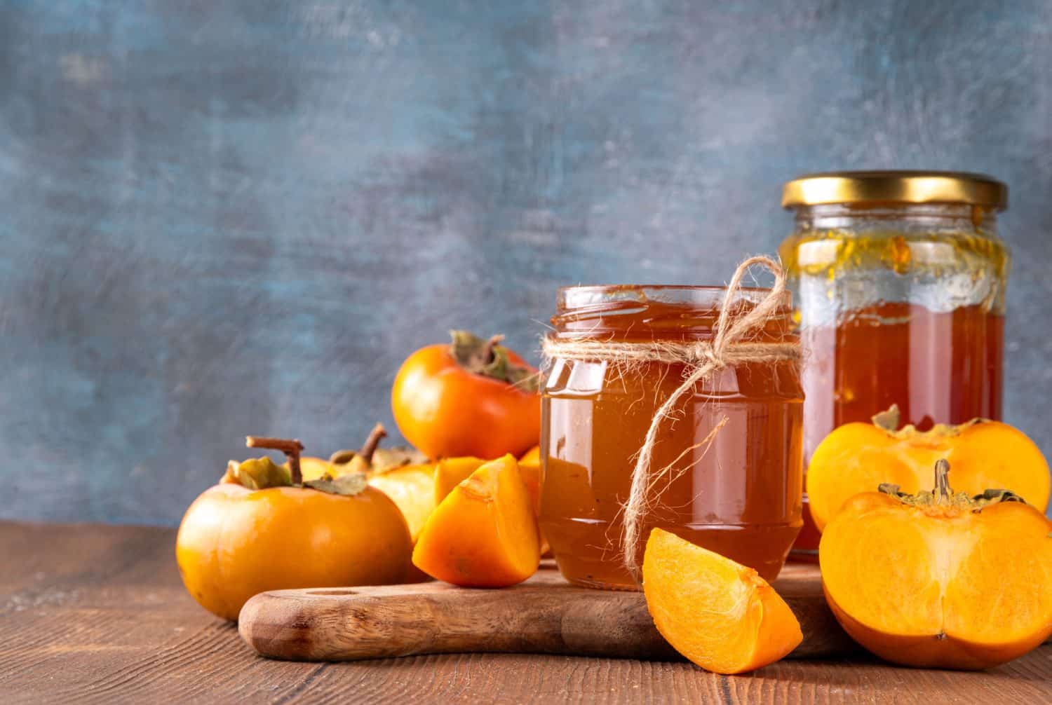 Persimmon jam. Sweet autumn homemade jam or marmalade canning preserves in a jar, with whole and cut persimmon in the background. Prices on These 30 Trader Joe's Items Just Dropped