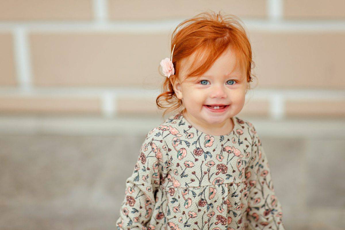 Red-haired baby girl smiling, close-up portrait