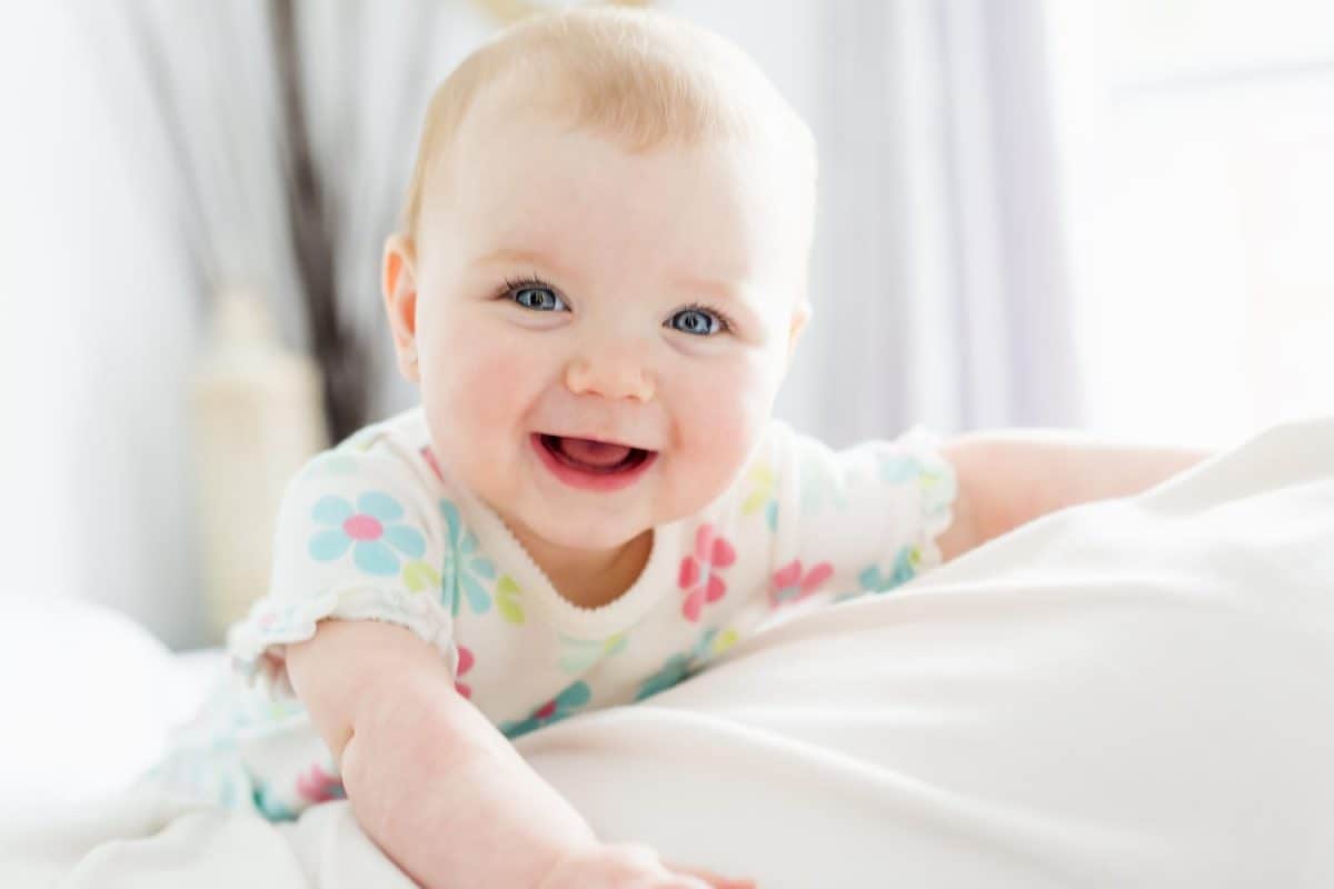 A Baby girl in white bedding at home look nice