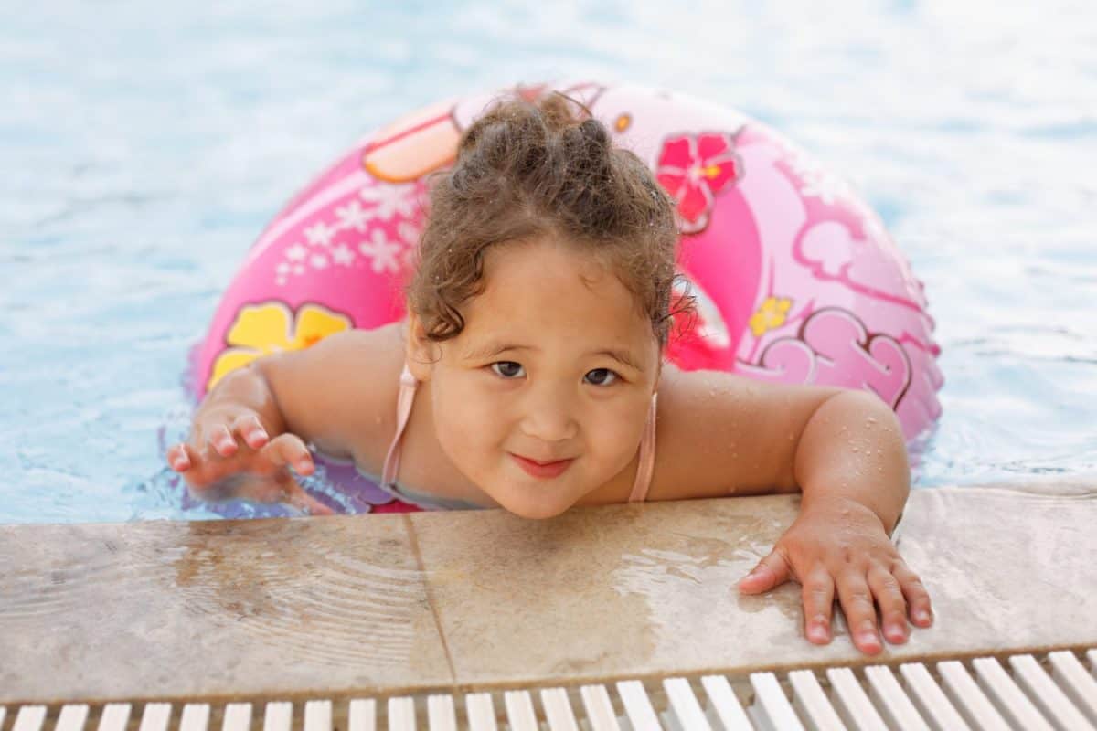 Pretty little kazakh curly girl playing by the swimming pool