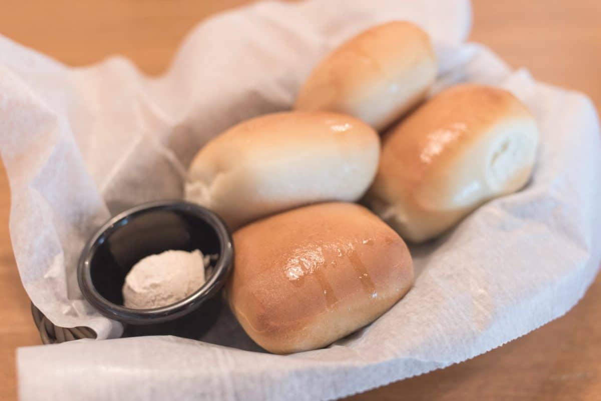 Texas Roadhouse Rolls with Cinnamon Honey Butter in a basket.