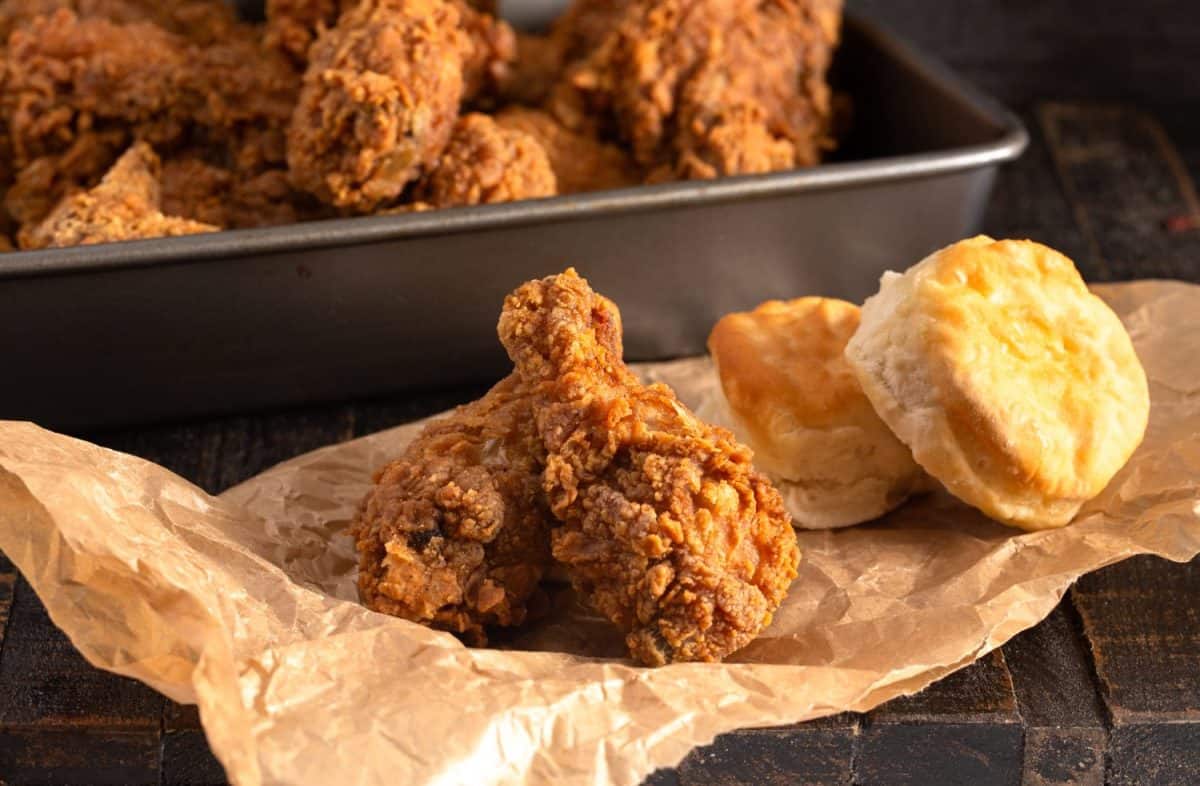 Homemade Crispy Chicken Drumsticks with Buttermilk Biscuits on a Rustic Wooden Table