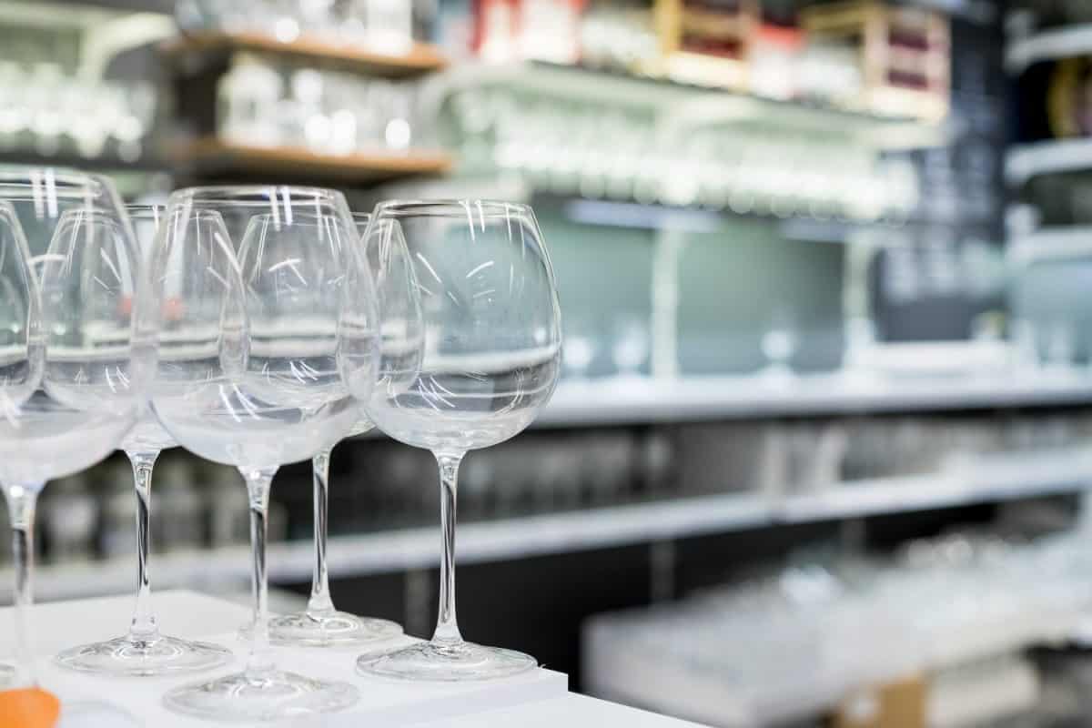 Shelves of modern stemware glasses for sale in store.Glasses and stemware set. Designer glassware on a glass shelf in a store.set tableware.modern home decor furnishings store. Shopping in retail