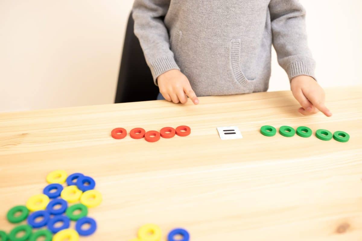 Preschool child is playing a math game, only hands are visible. Pointing gesture. Topic of comparison, counting, equal to. Concept of, early home schooling, mathematical thinking, interests. Caucasian