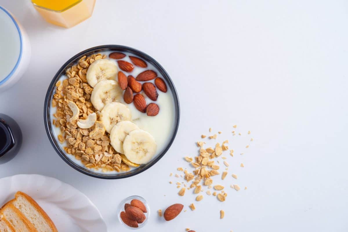 homemade healthy breakfas,Bowl with greek yogurt, banana granola and almonson,milks and orange juice and bread on white background.top view.