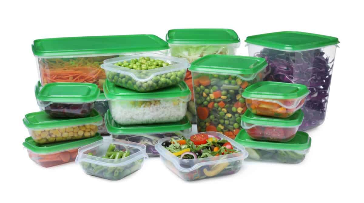 Plastic containers with fresh food on white background