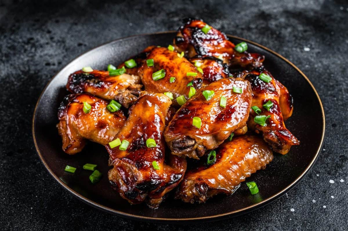 Baked chicken wings with sweet chili sauce in a plate. Black background. Top view.Forget Chick-fil-A Sauce, Americans Go Crazy for These 8 Condiments