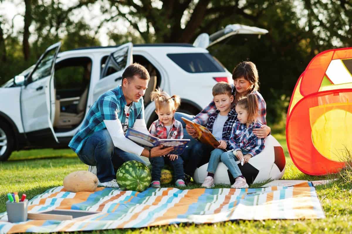 Family spending time together. Three kids. Outdoor picnic blanket.