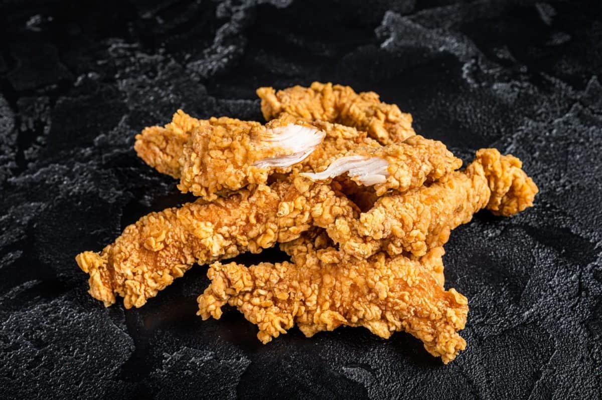 Breaded chicken strips Fingers, breaded breast meat. Black background. Top view.