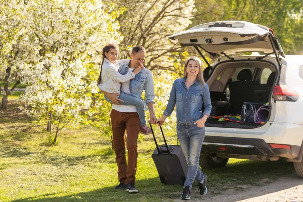 Family Enjoying. happy little girl with family near the car. Car insurance concept