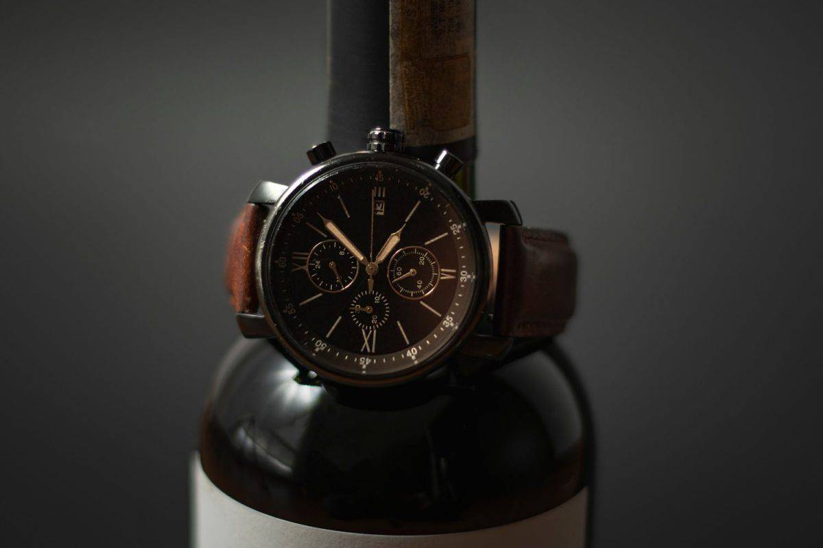 Luxury watch in a wine bottle with black background.