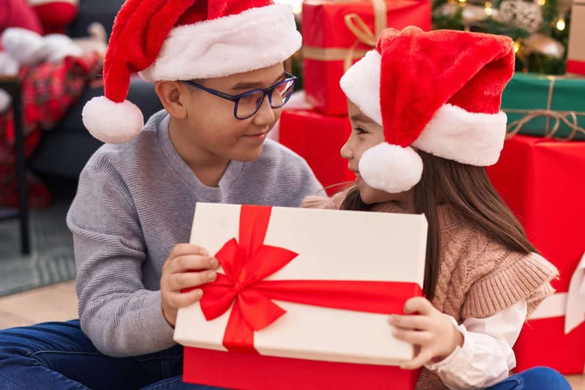 Brother and sister unpacking christmas gift sitting on floor at home