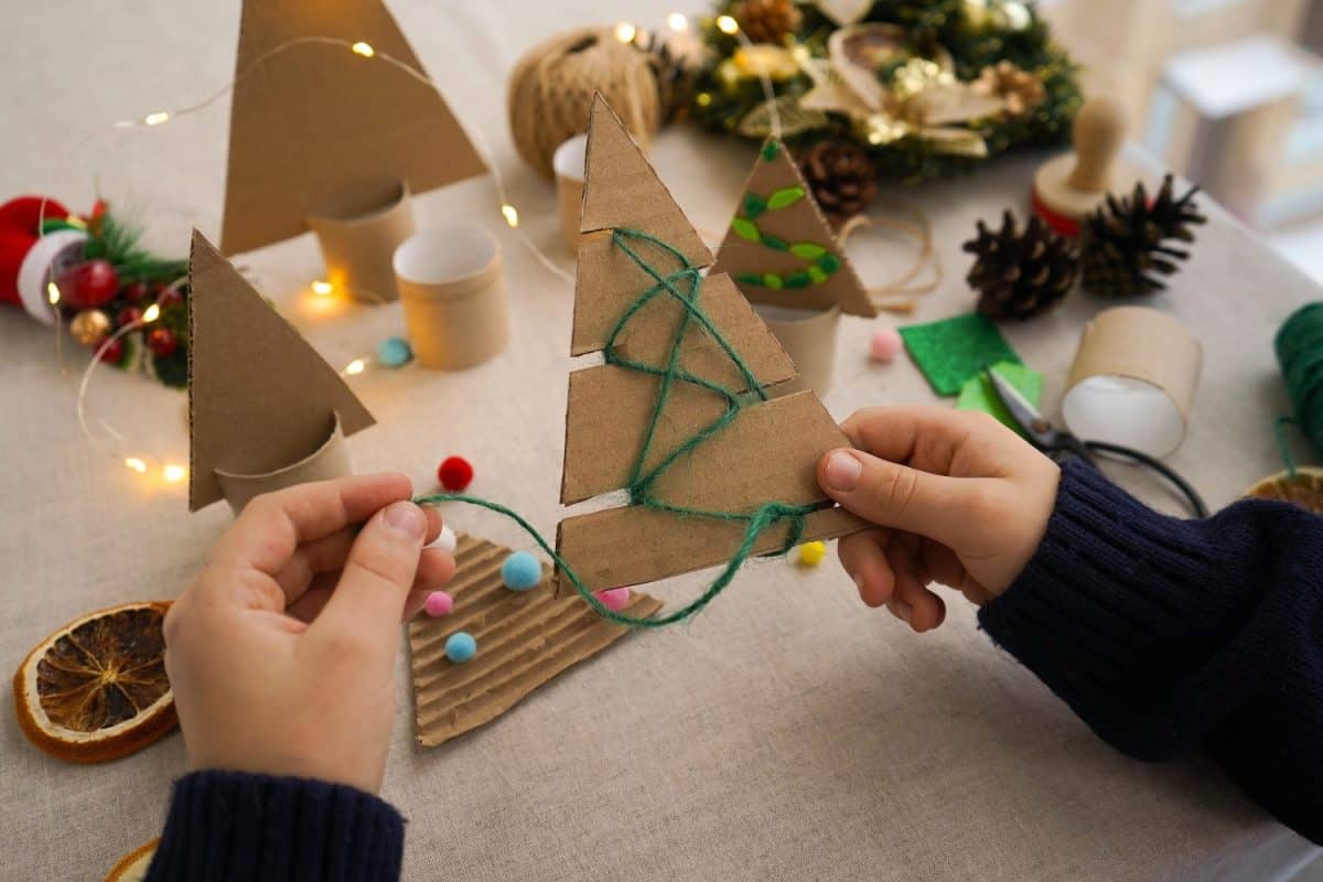 Handmade Christmas trees decoration. Children decorating Handmade Christmas tree with twine. View from behind the shoulder. Zero waste concept.