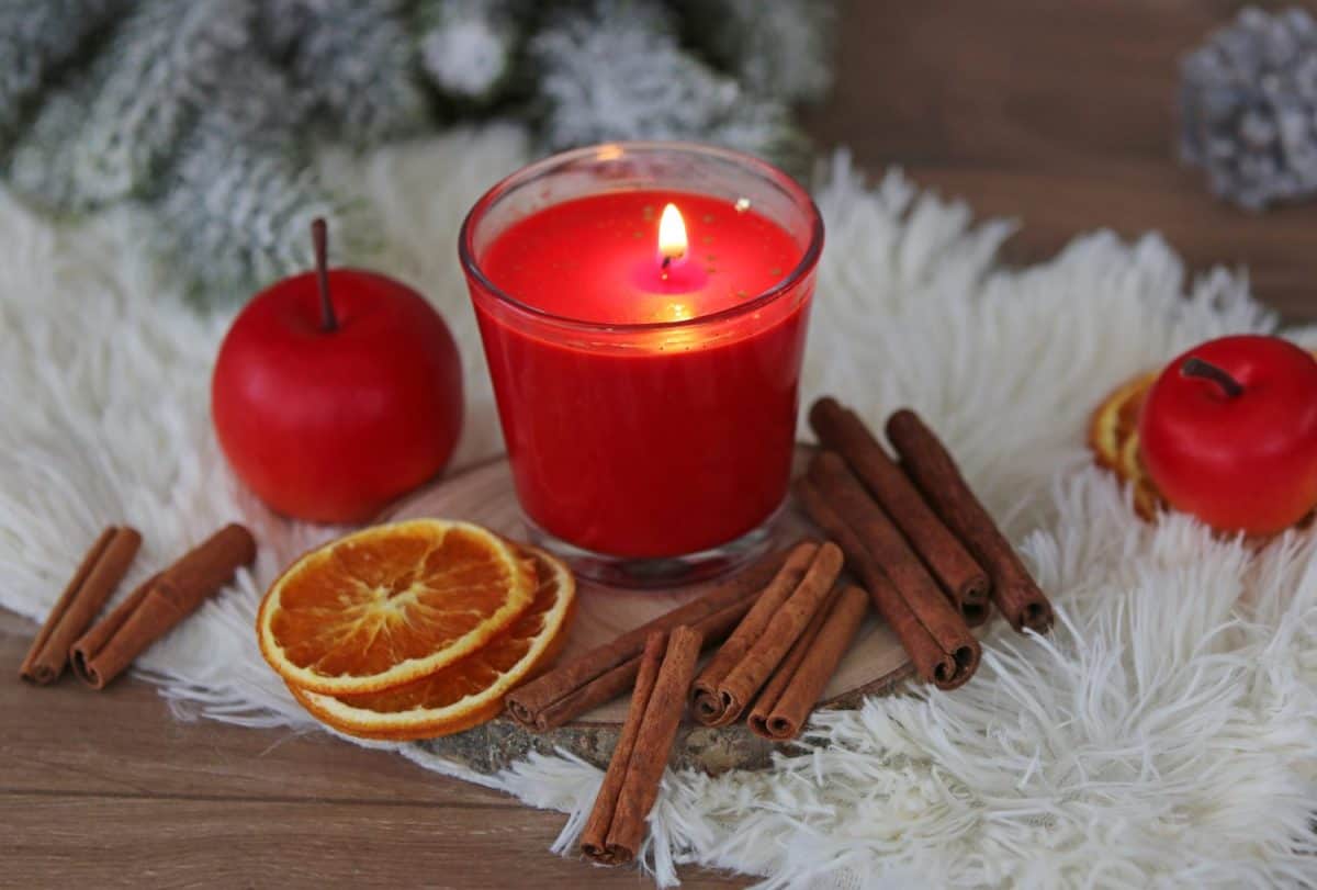 Christmas scented candle: aromatic candle with traditional winter spices, slices of oranges, apples and cinnamon sticks.