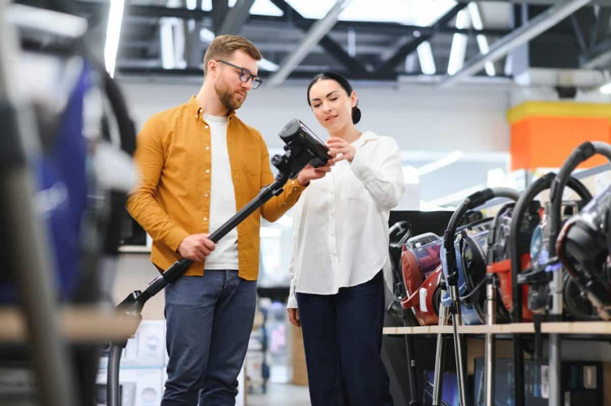 Young beautiful couple buying new vacuum cleaner at tech store. Having fun shopping time.