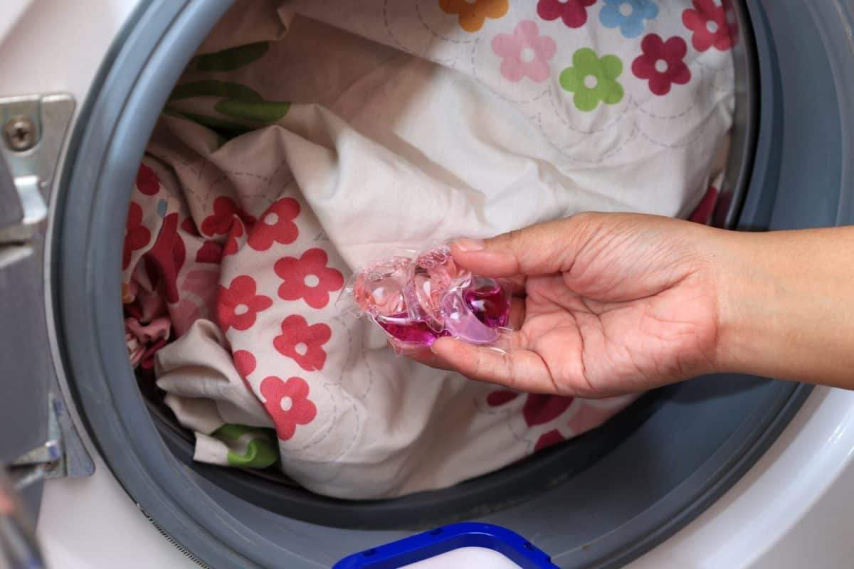 Woman Hand Hold Laundry Pod Gel. Laundry Detergent. Dirty Laundry in the Washing Machine. The 16 Best Household Essentials You Should Be Buying at Target