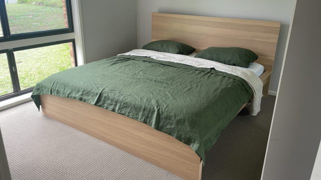 King size bed frame with mattress from Ikea, with green and white linen sheets