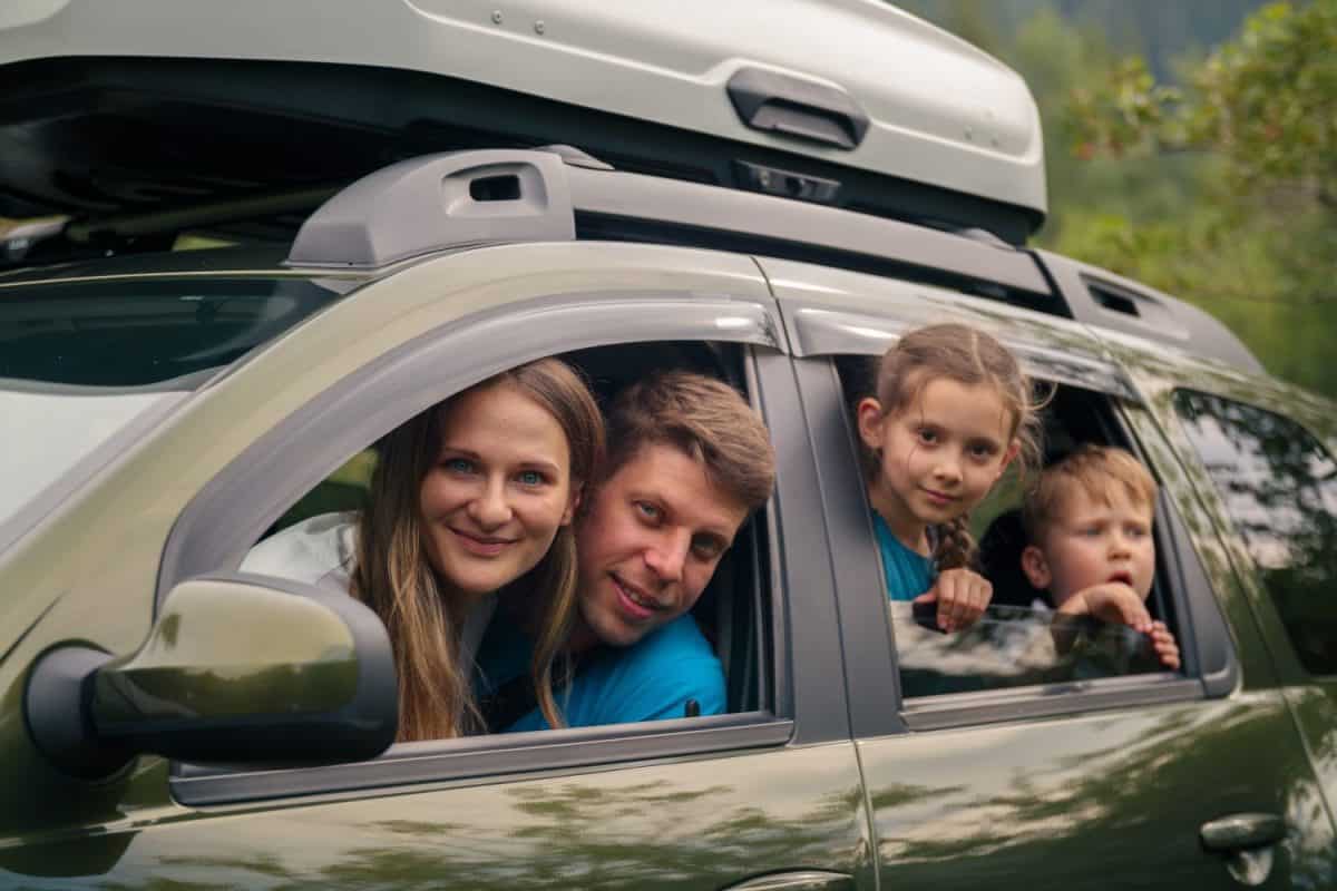 A joyful family is happily enjoying an exciting road trip in their spacious SUV surrounded by beautiful scenery