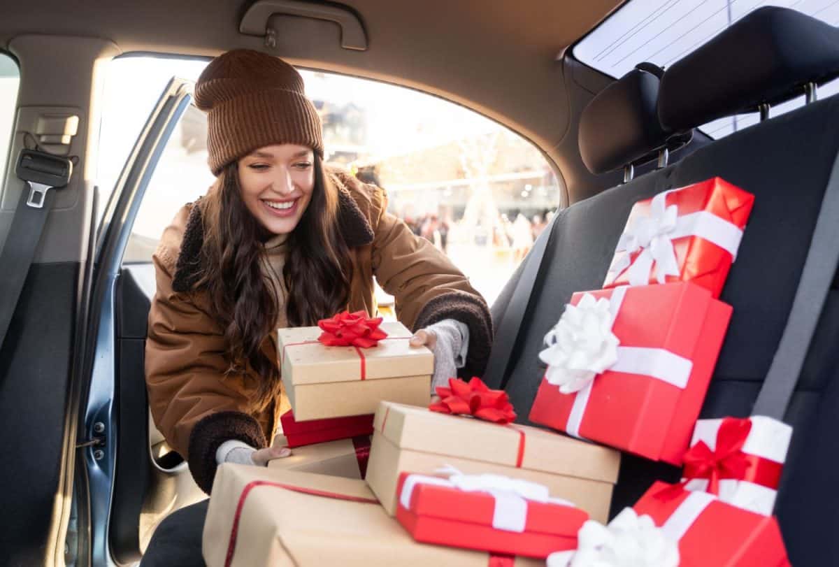 Woman delivering Christmas gifts. Young lady packing presents to her car, enjoy holiday spirit on winter day