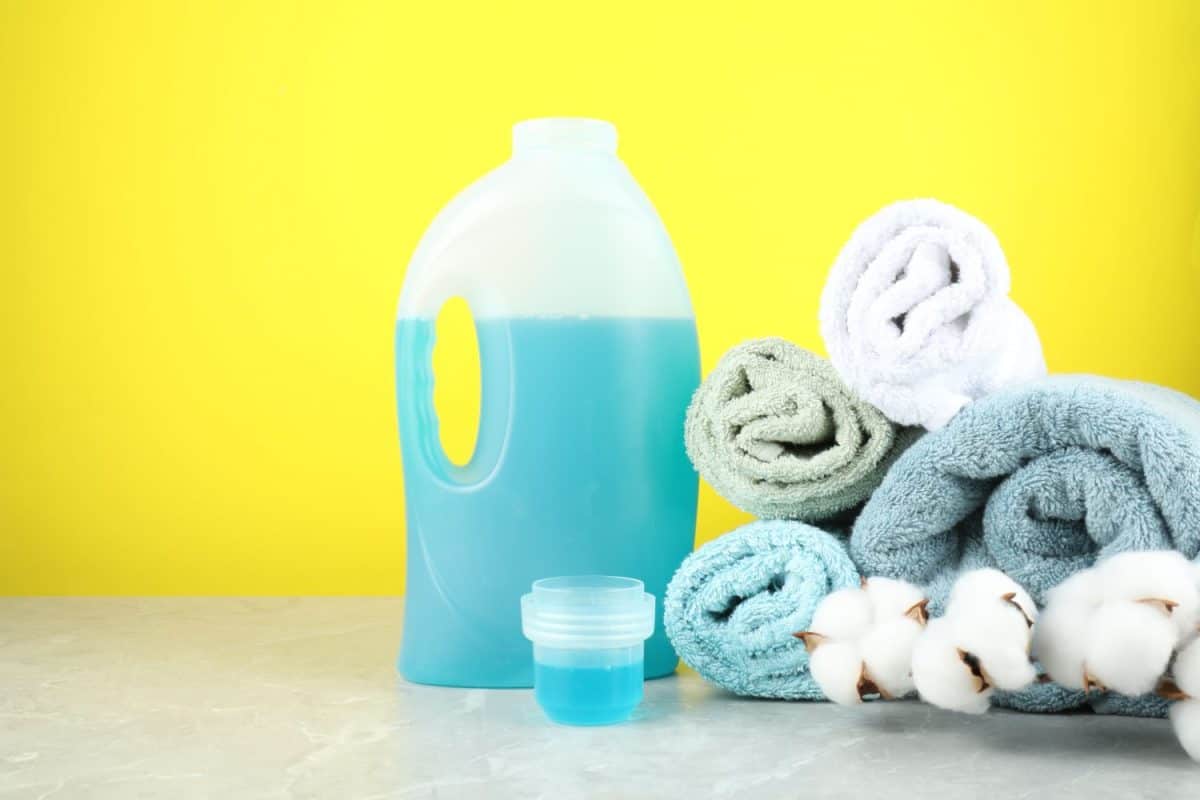 Laundry detergent in bottle, cap, cotton flowers and towels on grey marble table against yellow background, space for text. The 16 Best Household Essentials You Should Be Buying at Target