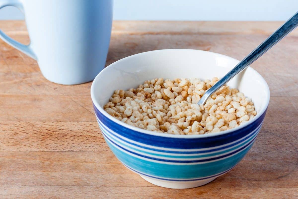 Puffed rice cereal in a striped blue bowl with a blue mug in the background