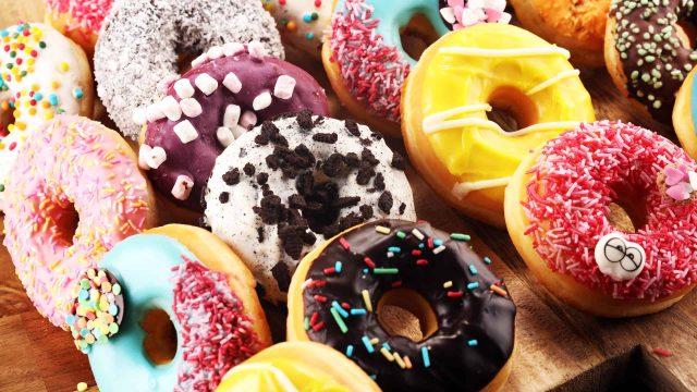 assorted donuts with chocolate frosted, pink glazed and sprinkles donuts.