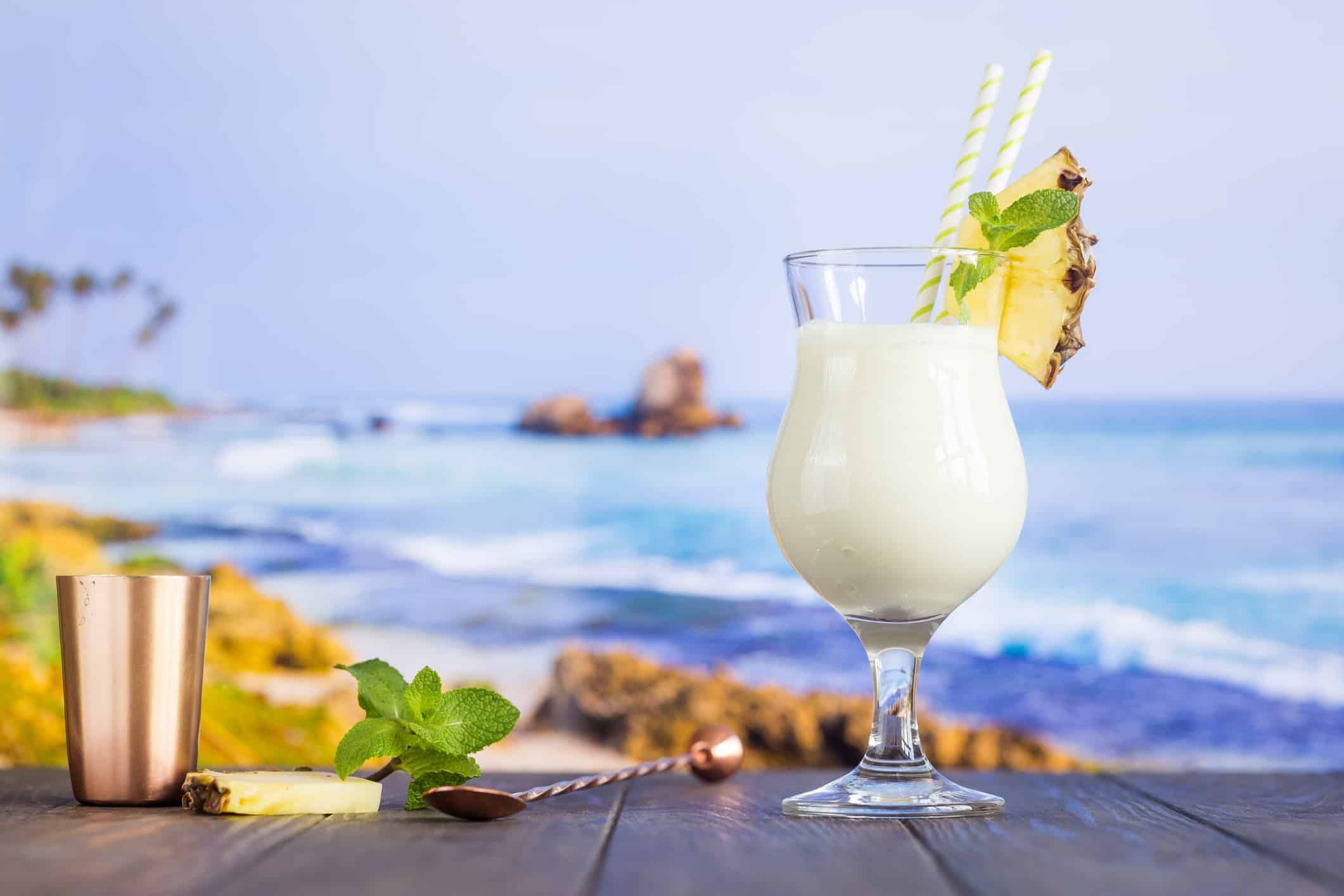 Cold pina colada cocktail in a glass on the beach with seascape background