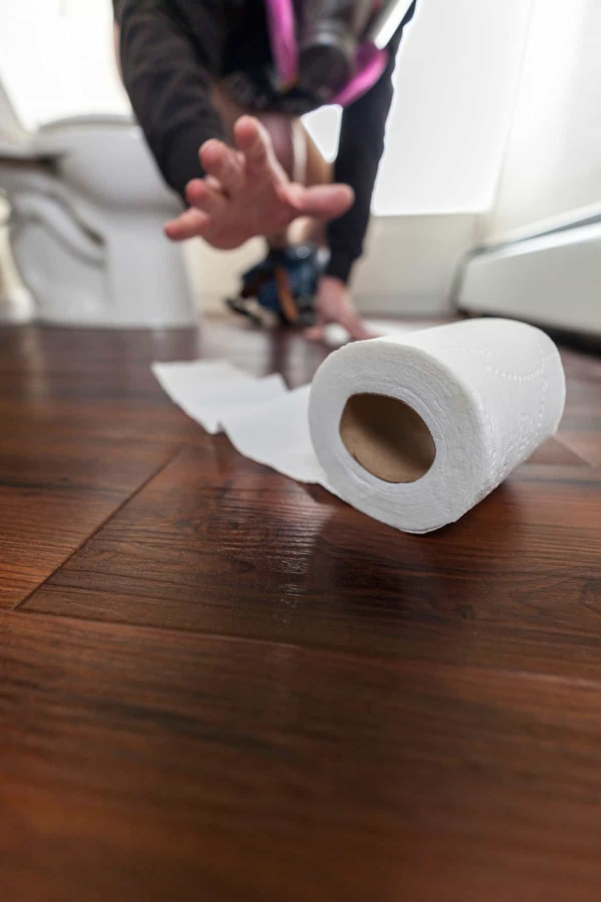 Toilet paper dropped on floor with man in gas mask trying to reach it. Charmin Was My Family's Favorite for Years, But These 8 Toilet Paper Brands Are Better