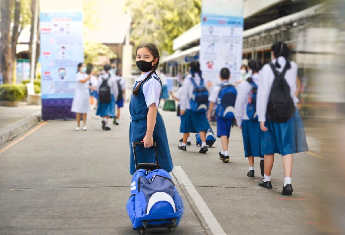 Portrait of Asian child in school uniform wearing face mask with school bag and social distancing protect from coronavirus covid-19. Back to school for new normal lifestyle concept.