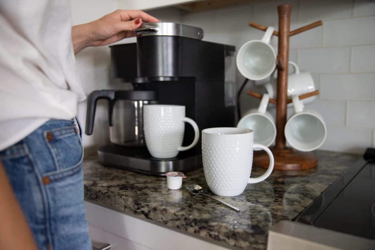 Coffee maker brewing coffee into a white cup