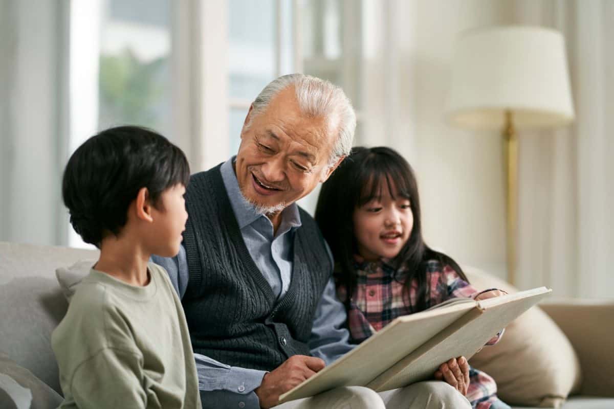 senior asian grandfather having a good time with two grandchildren at home